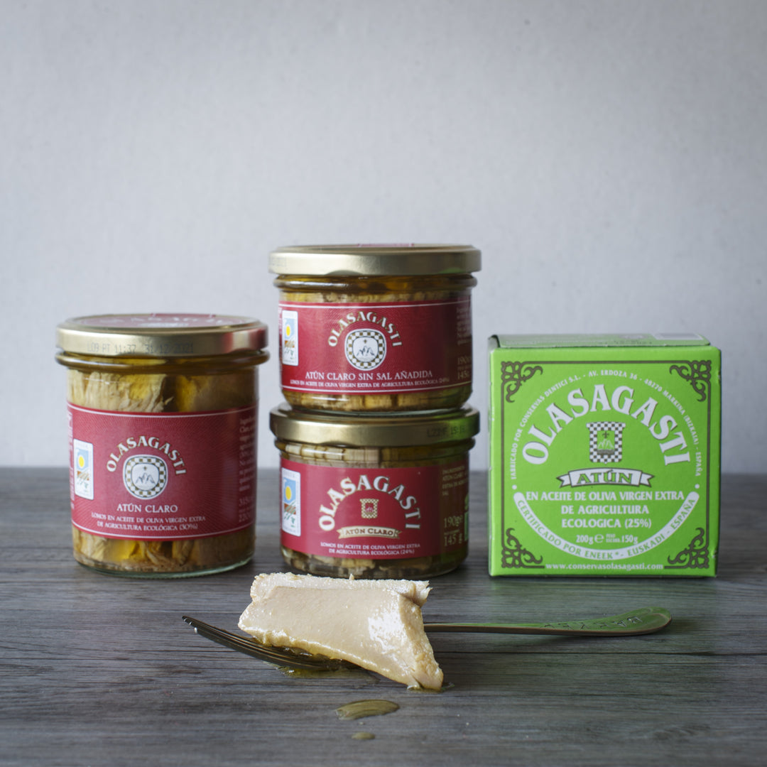 Photograph of 3 glass jars of clear tuna with no added salt, and a can of canned tuna in organic extra virgin olive oil, all from the Olasagasti brand