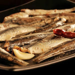 Dish with preserved sardines, with olive oil and a clove of garlic.