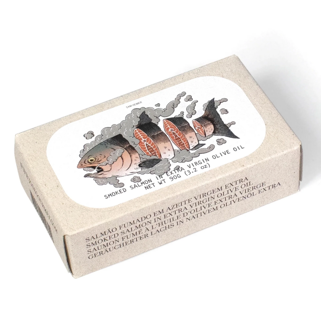 José Gourmet Smoked Salmon in Extra Virgin Olive Oil. The artistic cardboard packaging features a detailed illustration by Sam Heimer, showing a salmon sliced into pieces surrounded by grey smoke clouds. Premium Portuguese canned seafood combining artisanal smoking techniques with contemporary graphic art.